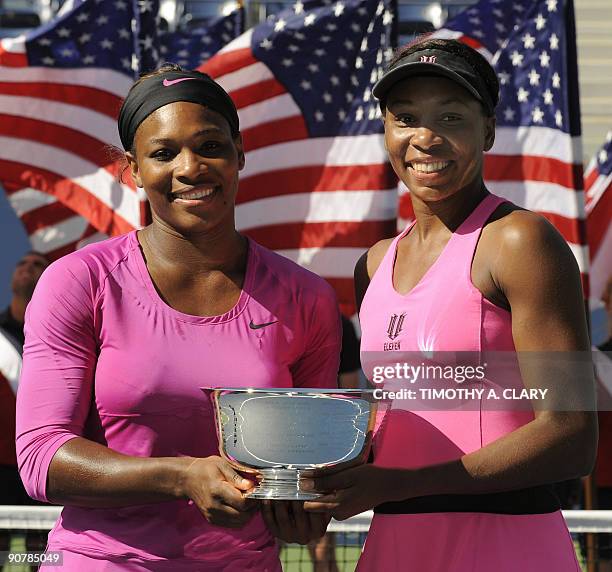 Sister Serena Williams and Venus Williams pose with the trophy after defeating Zimbabwe's Cara Black and Liezel Huber of the US 6-2, 6-2 in the US...