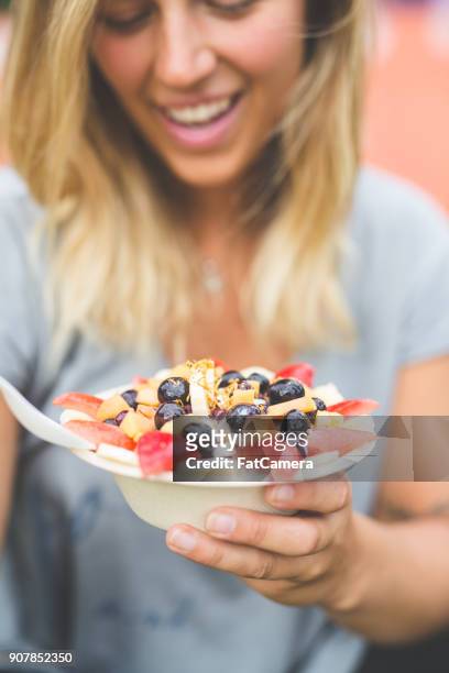 朝食スムージー ボウルを持って笑顔の女性が新鮮なフルーツをトッピング - acai ストックフォトと画像