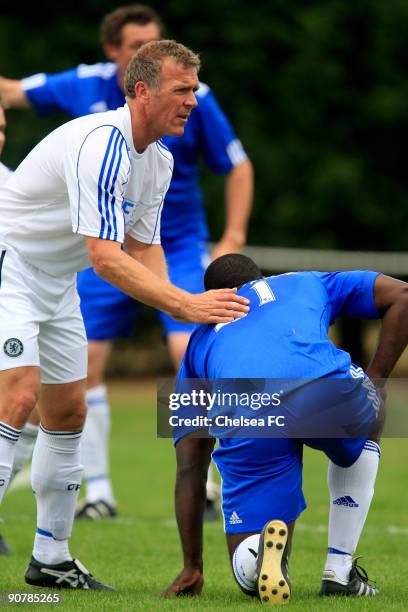 Former England cricketer Alex Stewart, and JDRF team player, helps up Chelsea's Jimmy Floyd Hasselbaink after tackling him during a Chelsea Old Boys...