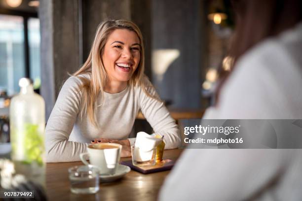 female friends talking and smiling in cafe - girlfriend stock pictures, royalty-free photos & images