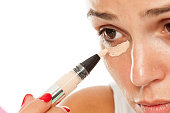 young women applied concealer under the eyes with applicator