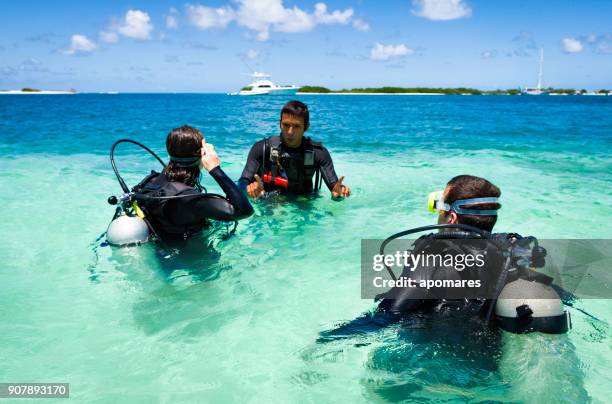dive master training a couple for first dive in a tropical turquoise island beach. - buceo stock pictures, royalty-free photos & images