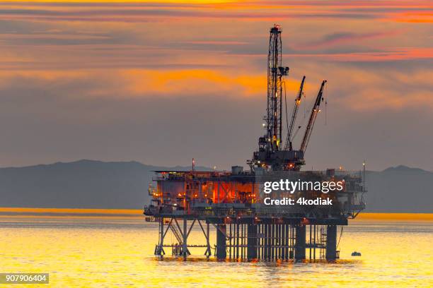 oil rig and surfer off the huntington beach in california - water's edge stock pictures, royalty-free photos & images