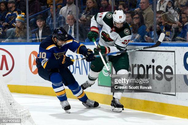 Brayden Schenn of the St. Louis Blues and Kyle Quincey of the Minnesota Wild battle for the puck at Scottrade Center on November 25, 2017 in St....