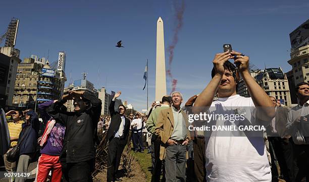 People gather to watch the acrobatics from the French Air Force Alphajets from the "Patrouille de France" air wing flying over 9 de Julio avenue in...