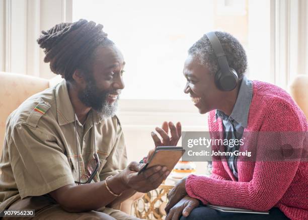 mature african couple using smartphone woman wearing headphones - jamaican culture stock pictures, royalty-free photos & images