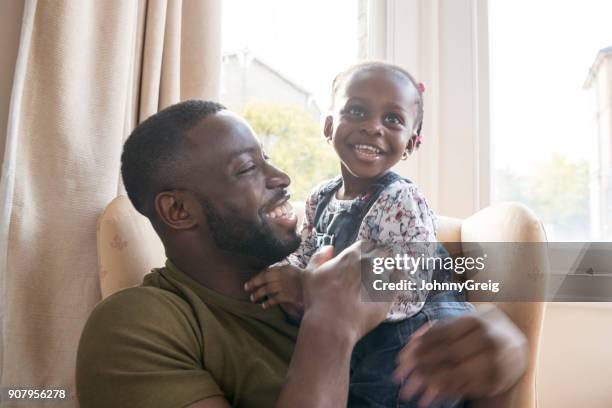 schattig jong meisje op vaders schoot glimlachen en op zoek weg - london not hipster not couple not love not sporty not businessman not businesswoman not young man no stockfoto's en -beelden