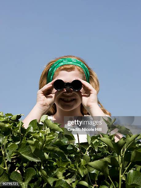 girl looking over a hedge with binoculars - nosey neighbor stock-fotos und bilder