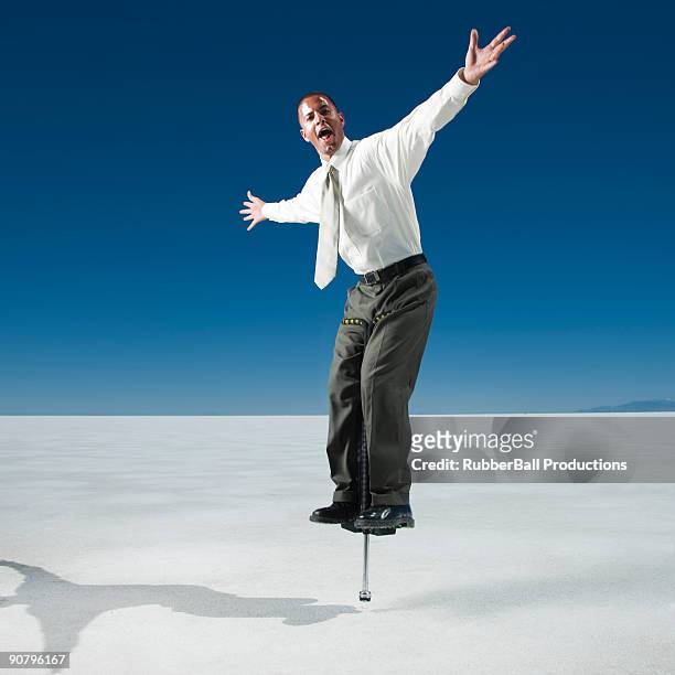 businessman on a pogo stick - pogo stick stock pictures, royalty-free photos & images