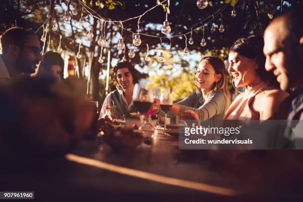 friends celebrating with wine and food at rustic countryside party - evening meal restaurant stock pictures, royalty-free photos & images