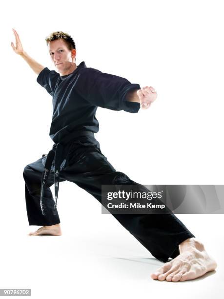 man in a black karate gi practicing martial arts - túnica fotografías e imágenes de stock