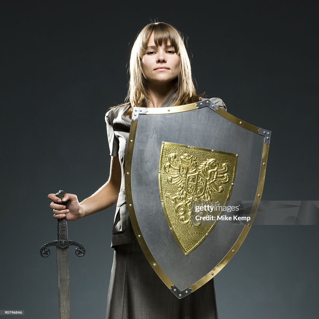 Businesswoman holding a sword and a shield