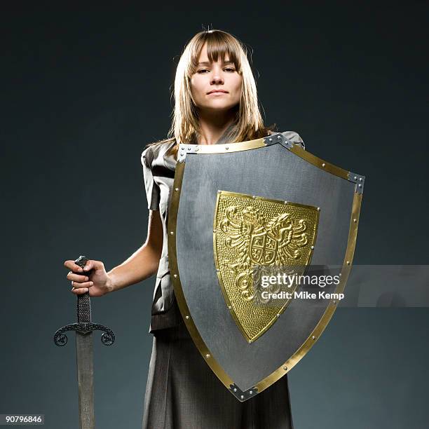 businesswoman holding a sword and a shield - business woman schild stockfoto's en -beelden