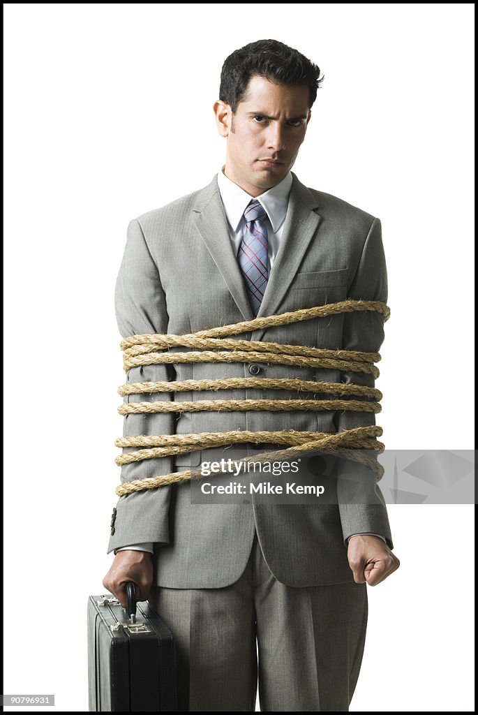 Businessman in a full suit tied up with a rope around his mid section