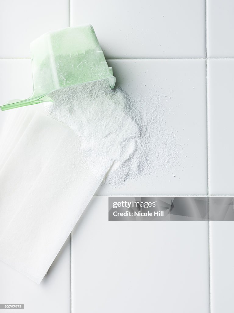 Laundry detergent and dryer sheet on a white tile countertop