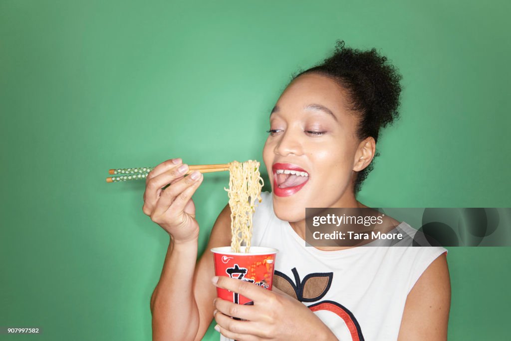 Woman eating takeaway noodles with chopsticks