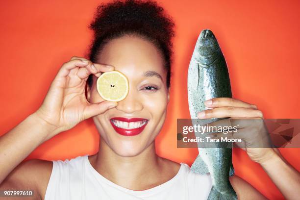 woman holding lemon and fish - omega 3 stock pictures, royalty-free photos & images