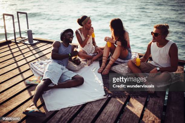 young multi-ethnic hipster friends and couples relaxing on jetty - beach picnic stock pictures, royalty-free photos & images