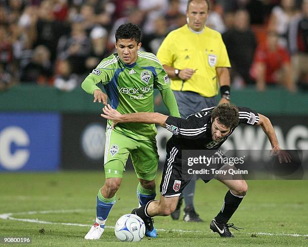 Ben Olsen of D.C. United falls as he is tackled by Fredy Montero of Seattle Sounders FC during an MLS match at RFK Stadium on September 12, 2009 in...
