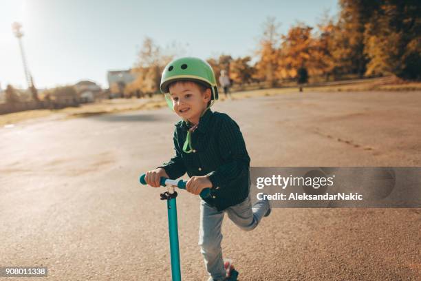 kleiner junge eine push-motorroller - tretroller stock-fotos und bilder