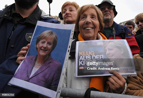 Supporter Helga Schuetz shows pictures of German Chancellor Angela Merkel during an election campaign rally on September 15, 2009 in Koblenz,...