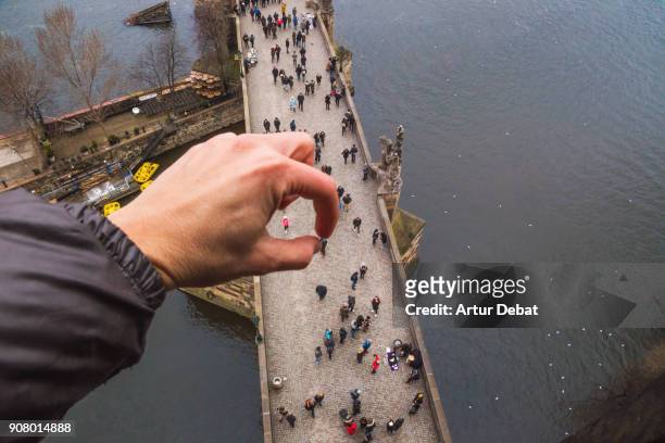 funny picture using perspective to blow the mind creating the effect of picking people with hand like giant from the charles bridge of prague from elevated viewpoint. - walking personal perspective stock pictures, royalty-free photos & images