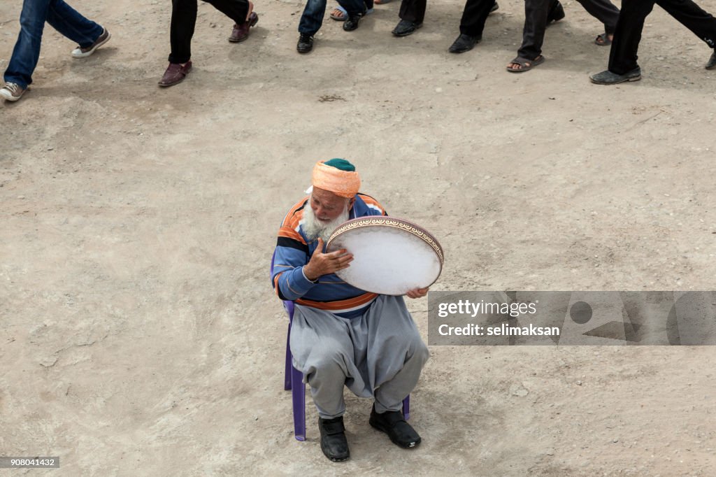 Senior Sufi homem com barba branca tocando pandeiro para dançar pessoas