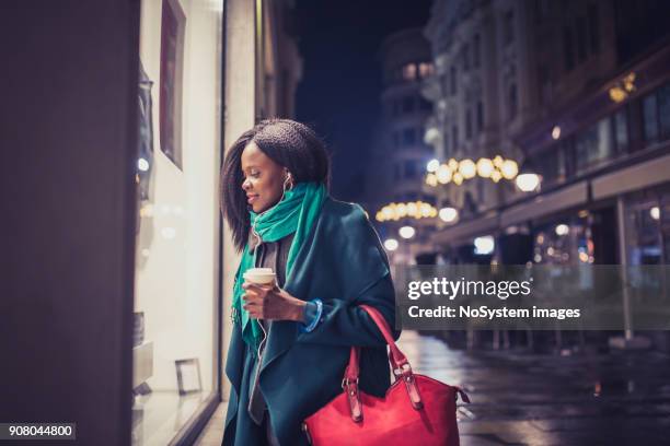 young woman, african - american ethnicity, looking at the shop window. it's christmas time - window shopping stock pictures, royalty-free photos & images