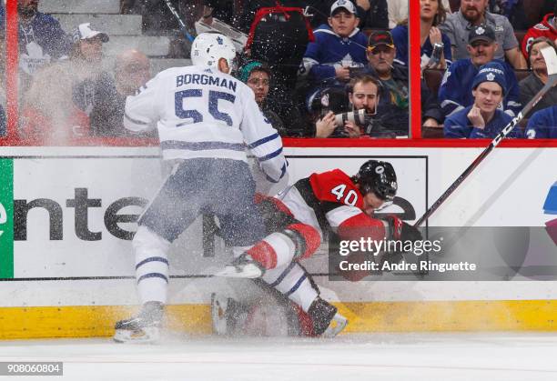 Andreas Borgman of the Toronto Maple Leafs body checks Gabriel Dumont of the Ottawa Senators into the side boards at Canadian Tire Centre on January...