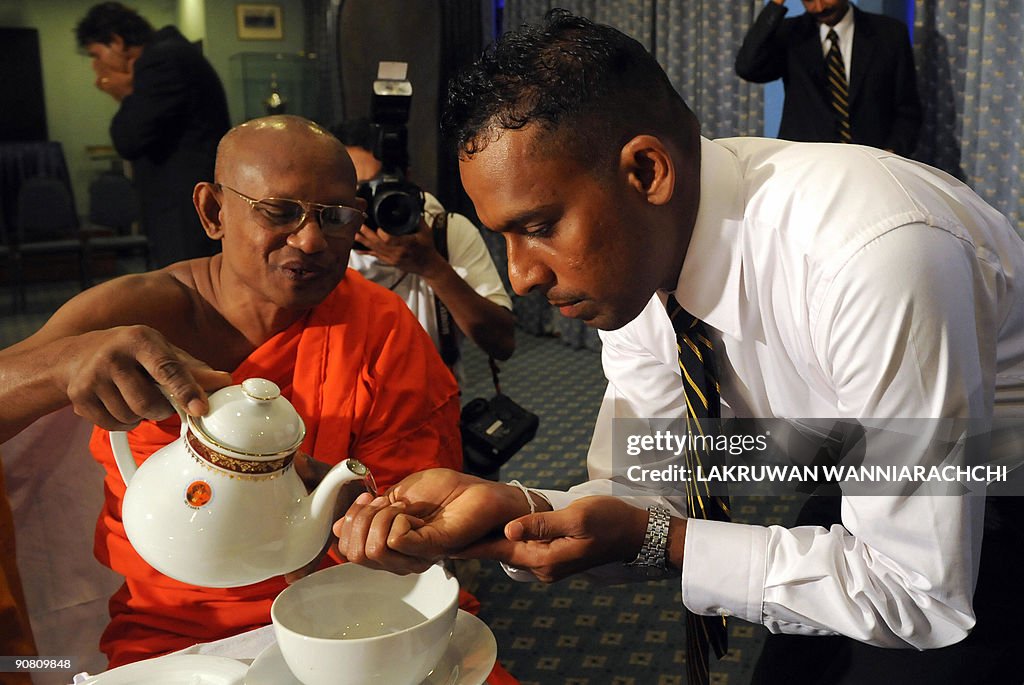 A Sri Lankan Buddhist monk (L) pours wat