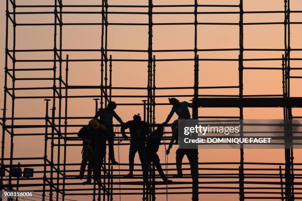 This photograph taken on January 20, 2018 shows Indian workers fixing a metal structure near the India Gate for the upcoming Indian Republic Day...