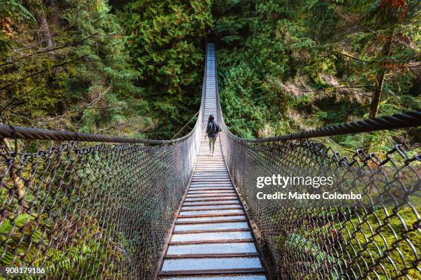 woman walking on suspension bridge, vancouver - vancouver bridge stock pictures, royalty-free photos & images