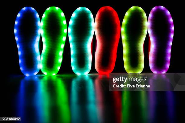 glowing soles of three pairs of led lit shoes - purple shoe stock pictures, royalty-free photos & images