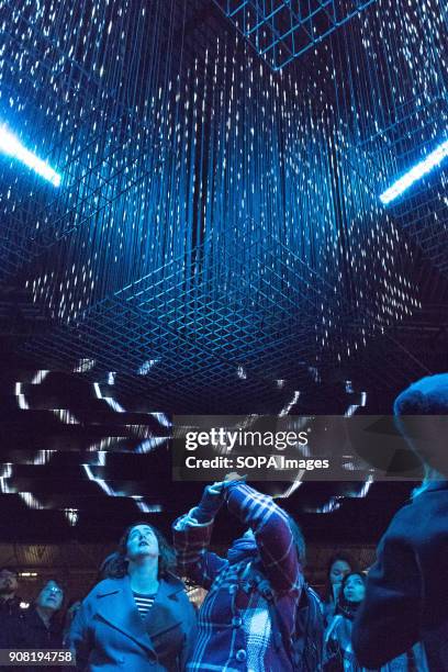 The crowd looking upwards and capturing the overhead light installations in King's Cross during Lumiere London.