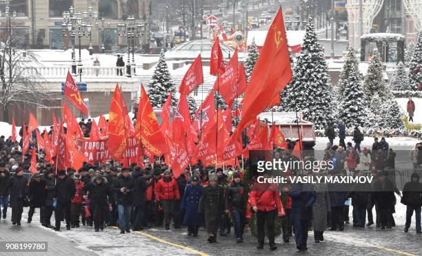 Russian Communist Party supporters carry red flags as they take part in a memorial ceremony to mark the 94th anniversary of the death of Russian...