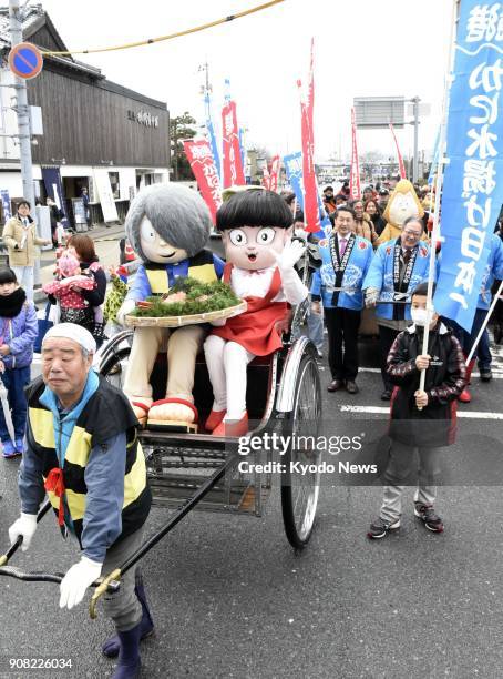 Characters from the popular horror comic series "Gegege no Kitaro" ride in a rickshaw with a plate of crabs to dedicate to Yokai Shrine during a...