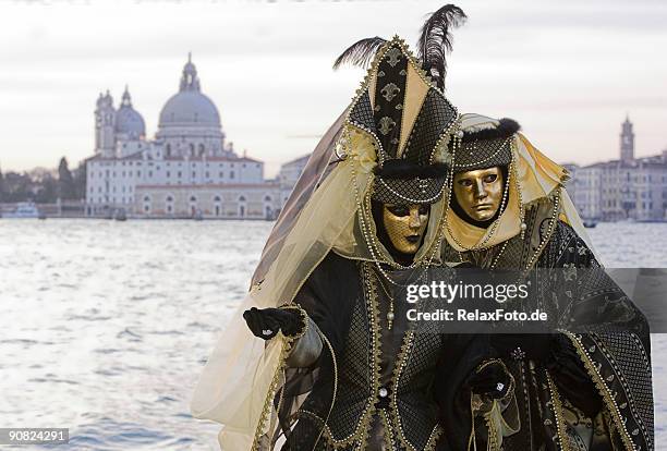 couple of golden venetian masks at grand canal (xl) - santa maria della salute celebrations in venice stock pictures, royalty-free photos & images