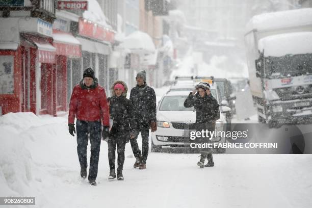 People walk in a street of Davos on January 21 as snow falls on the eve of the opening of the World Economic Forum 2018 annual meeting in Davos. The...