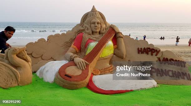 Visitors look near to the Goddess Saraswati's sand sculpture as it is creating by sand artist Manas Sahoo on the eve of Basanta Panchami or Saraswati...