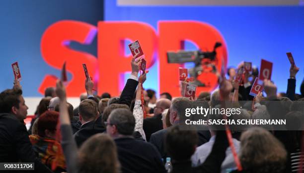 Delegates of Germany's social democratic SPD party hold up their voting cards during an extraordinary SPD party congress in Bonn, western Germany, on...