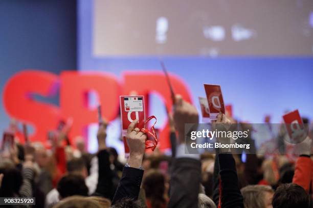 Delegates hold their passes in the air to indicate a vote during a party conference in Bonn, Germany, on Sunday, Jan. 21, 2018. German Chancellor...