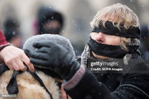 Woman helps a protestor to put black bands over her eyes and mouth during a silent assembly named Stolen Justice in Krakow. Stolen Justice happening,...