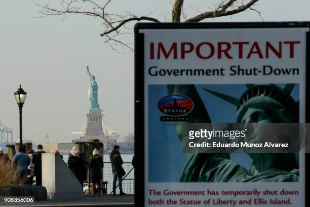 Shutdown placard is seen at the entrance of the Liberty State ferry terminal as people look on in Battery Park on January 21, 2018 in New York City....