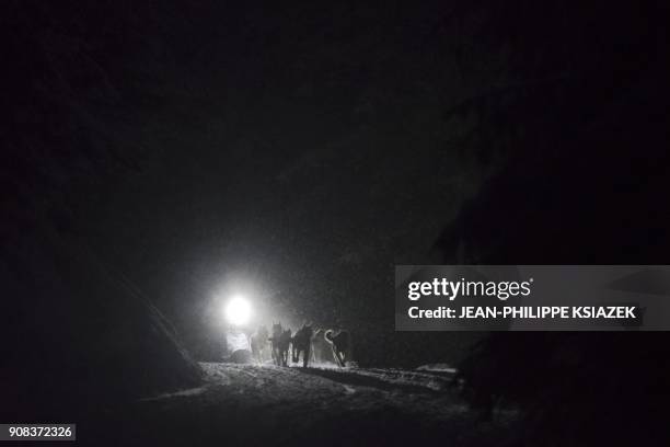 Musher and his sledding dogs race by night during a stage in Val-Cenis during the 14th edition of "La Grande Odyssee" sledding race across the Alps...