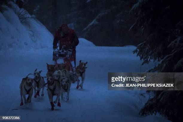 Musher and his sledding dogs race by night during a stage in Val-Cenis during the 14th edition of "La Grande Odyssee" sledding race across the Alps...