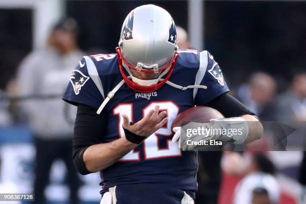 Tom Brady of the New England Patriots looks at his right hand during warm ups before the AFC Championship Game against the Jacksonville Jaguars at...