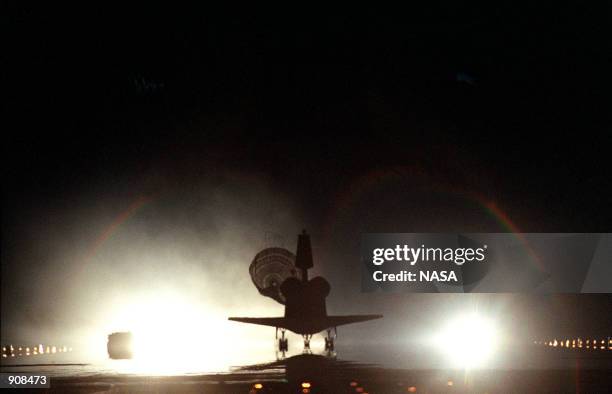 The Space Shuttle orbiter Columbia, with its drag chute deployed, touches down on runway 33 at the Shuttle Landing Facility after a successful...