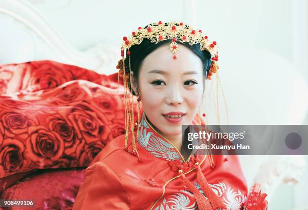 bride wearing wedding dress sitting on bed - chinese wedding dress stock pictures, royalty-free photos & images