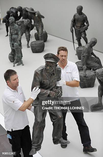 Gallery employees carry one of the sculptures during the preparations fro the exhibition "Art for millions - 100 sculptures from the Mao era" at the...