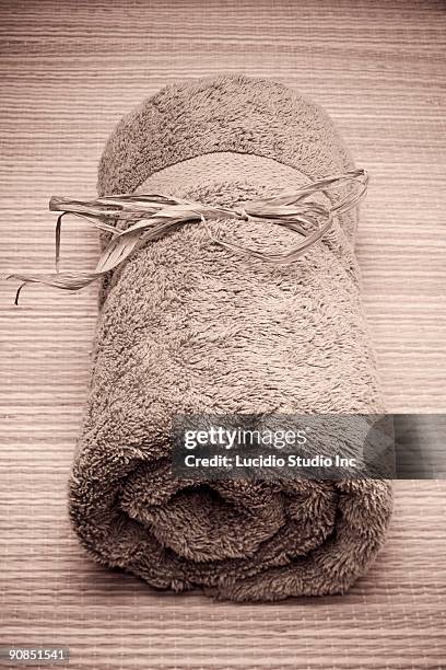 rolled up bath towel on a straw mat - rieten mat stockfoto's en -beelden